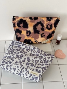 Close-up of leopard print makeup bags in brown and grey canvas with metal zippers