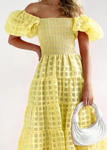 Detail of off-shoulder puff sleeve dress featuring yellow plaid texture and tiered skirt
