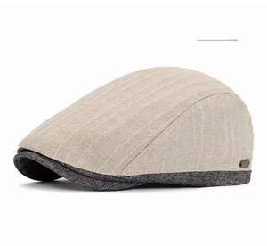 Detail of beige newsboy hat with grey peak, striped cotton texture and metal logo