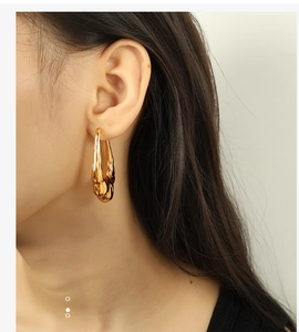 Close-up of model wearing chunky 18K gold plated lava-style hollow hoop earrings