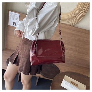 Gros plan d'un sac à bandoulière en cuir verni rouge foncé avec chaîne en métal chic
