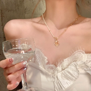 Gros plan d'un collier pendentif feuille d'érable plaqué or avec perles sur un mannequin