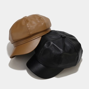 Top view of PU leather newsboy hats in black and caramel brown with button detail