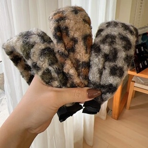 Three leopard print plush hairbands in dark brown, beige, and grey held by hand
