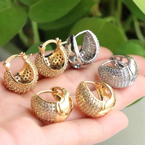 Détail de boucles d'oreilles boules évidées avec zircons sertis en doré et argenté
