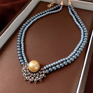 Détail du collier de perles bleues à deux rangs avec pendentif floral doré strass