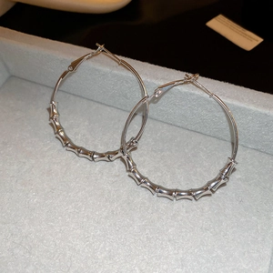 Detailed view of silver bamboo joint hoop earrings on a grey velvet jewelry tray