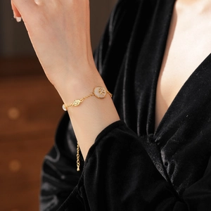 Close-up of a gold star charm bracelet with white stone inlay on a velvet sleeve