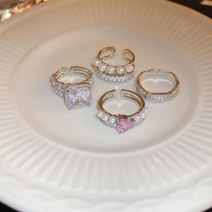 Détail d'un ensemble de quatre bagues argentées avec zircon et perle sur assiette