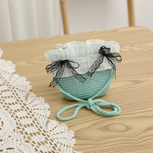 Détail du sac en paille vert menthe avec bordure en dentelle et nœuds papillon noirs