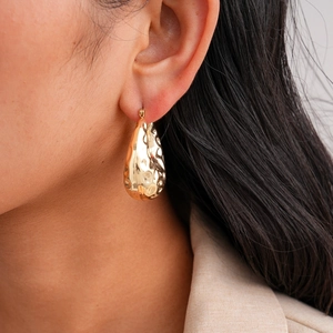 Close-up of gold water drop earrings with hammered texture on a model showing refined detail