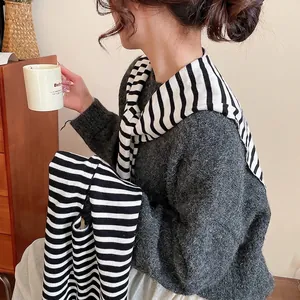Chic dark grey mohair sweater styled with a black and white striped knitted shawl accessory