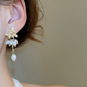 Detailed view of floral pearl tassel earrings featuring gold flower charms on model