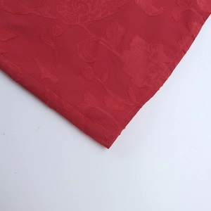 Macro detail of red floral jacquard fabric showing silky texture and intricate patterns