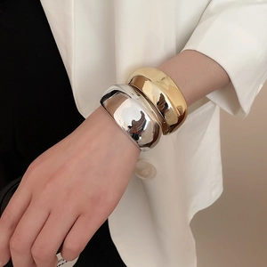 Dettaglio di bracciali a polsino geometrici lucidi nei colori oro e argento
