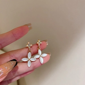 Detailed macro view of gold star stud with white opal clover dangling drop earring