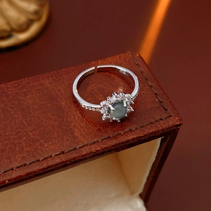 Detail of silver sunflower open ring featuring a green cat eye stone on dark leather
