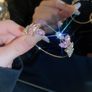 Detailed view of leaf-shaped sparkling crystals on a gold-plated adjustable bangle
