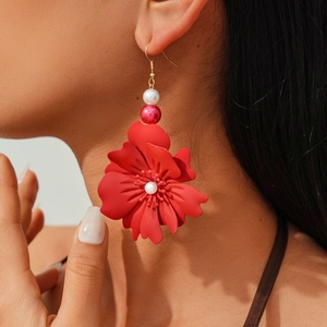 Detailed view of oversized red floral earrings with white and pink pearls on model