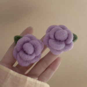Macro view of velvet-textured purple flower earrings with green leaf accents