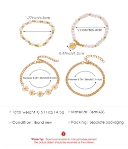 Detail of bohemian layered beaded bracelets set with starfish and daisy charms
