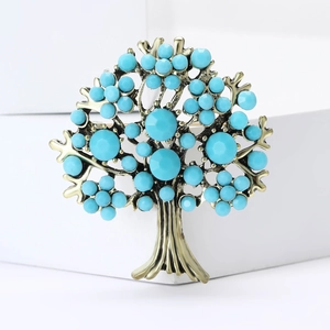 Detail of tree of life brooch featuring bronze metal and blue rhinestones on white background