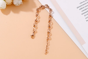 Detail of rose gold S-link chain bracelet with lobster clasp on floral background