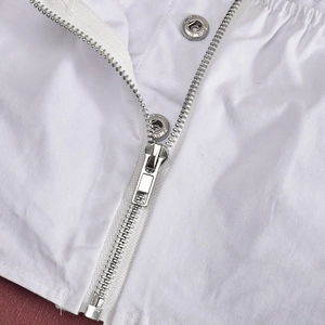 Close-up of high-quality silver metal zipper and snap button on white pleated skirt