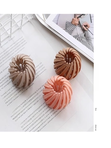 Close-up of matte beige, pink, and coral bird nest hair clips on a fashion magazine