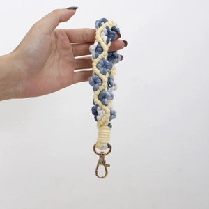 Detailed view of handmade woven floral keychain with blue and beige cotton cords