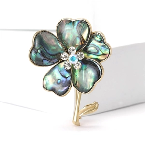 Elegant gold clover brooch with abalone shell petals and sparkling blue rhinestones