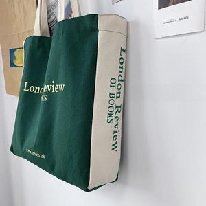 Vista laterale della borsa tote in tela verde e beige con stampa London Review of Books