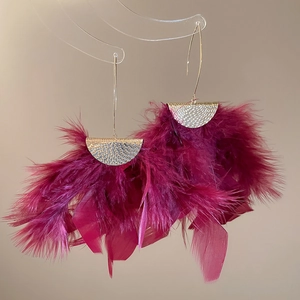 Detailed view of magenta feather tassel earrings with textured gold metal accents