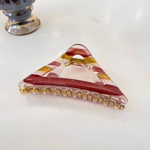 Detailed view of triangular tortoiseshell claw clip with red and yellow marble texture