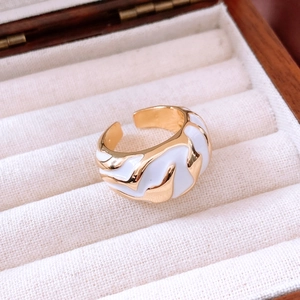 Close-up of golden irregular wavy ring with white enamel in a wooden jewelry box