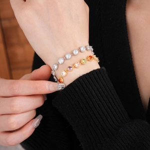Detailed close-up of heart-cut colorful zircon bracelets on a black sweater sleeve