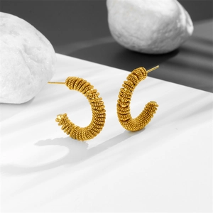 Golden spiral C-shaped stainless steel earrings on natural white textured stones