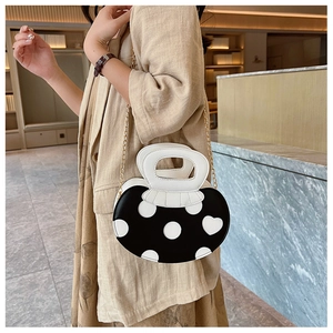 Detail of sweet mushroom-shaped handbag featuring polka dots, hearts and gold chain strap