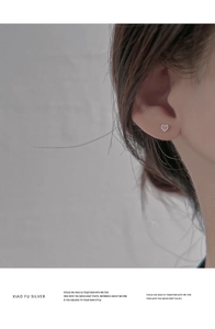 Macro shot of a heart-shaped stud earring with a pink gemstone worn on the ear
