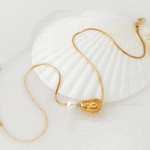 316L stainless steel necklace with gold heart pendant and pearl on a white sea shell