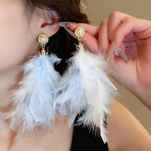 Elegant gold feather tassel earrings with pearl stud shown on a fashion model