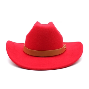 Macro detail of red wool cowboy hat featuring brown leather band and golden stud