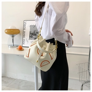 Detail of white bucket bag with orange fruit patch and adjustable shoulder strap
