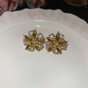 Detail shot of vintage green floral stud earrings with diamonds on a white ceramic dish