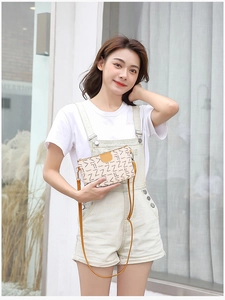 Detail of crossbody bag with beige floral print, gold hardware and leather flap