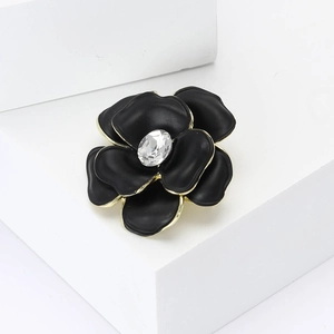 Exquisite black enamel flower brooch with gold edges and central sparkling crystal
