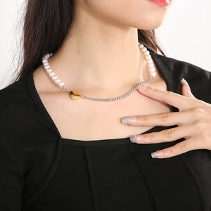 Close-up of cuban chain necklace with white pearls and gold heart pendant on model