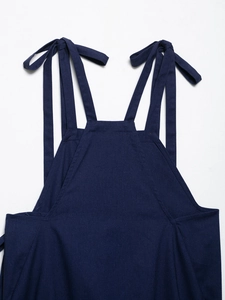 Detail of adjustable bow-tie shoulder straps on a navy blue linen top with twill fabric texture