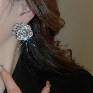 Close-up of sparkling silver flower stud earring with rhinestones on model's ear