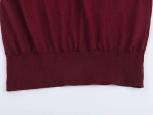 Gros plan d'un pull polo en maille fine bordeaux avec bord-côte sur fond blanc immaculé
